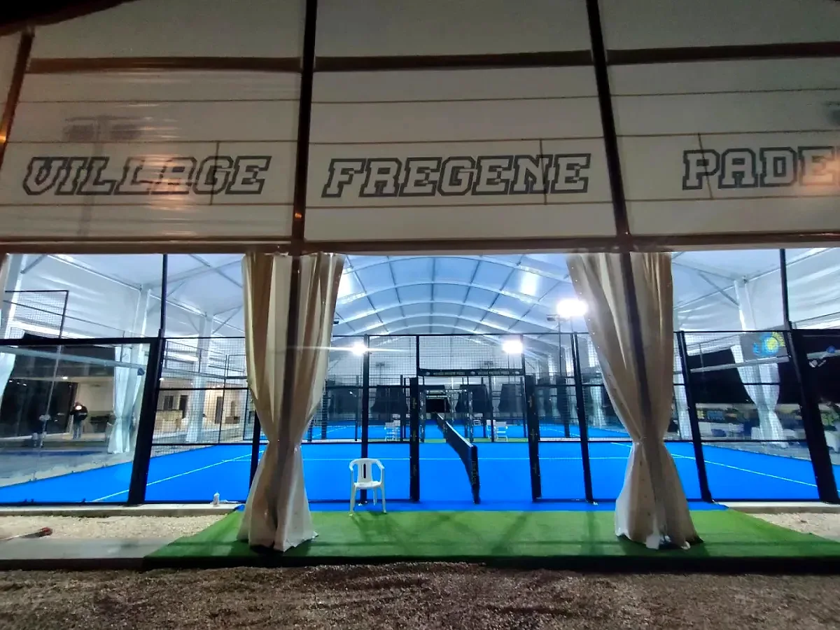 Campi da padel coperti di sera con insegna Village Fregene Padel
